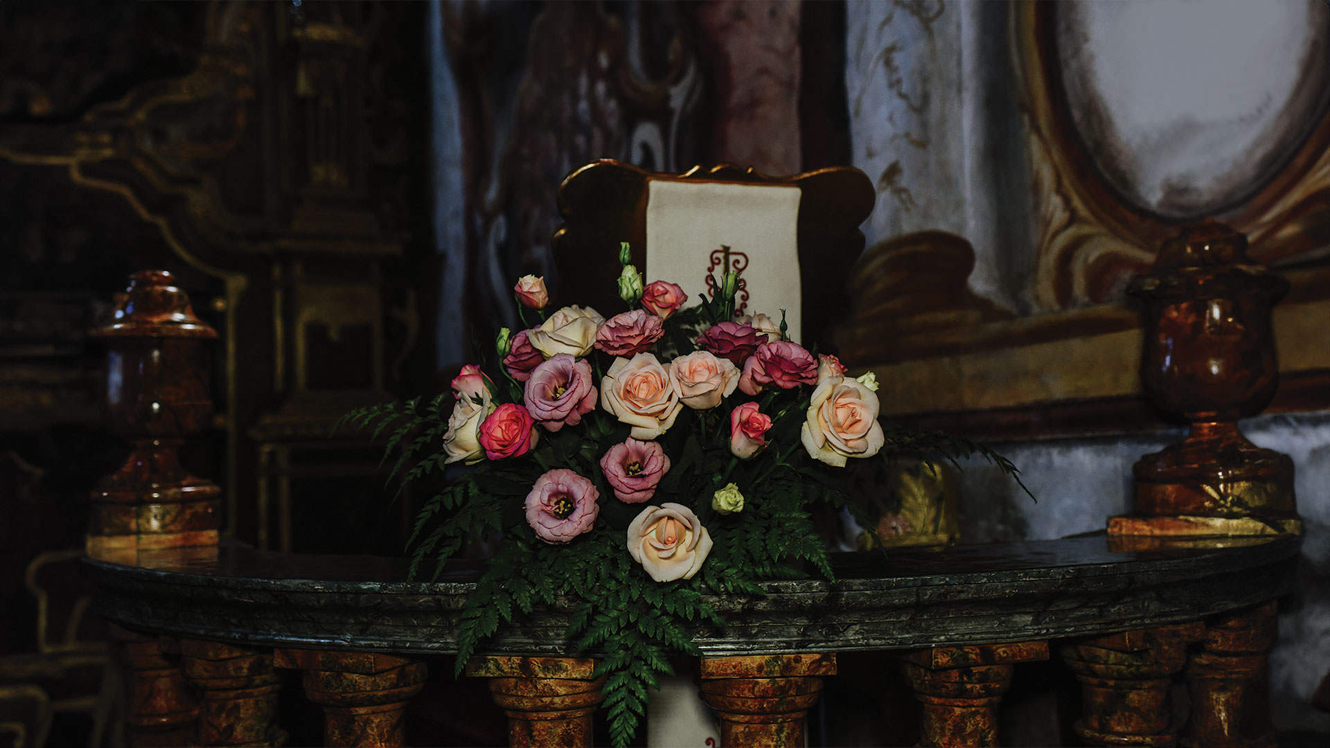 Aranjament floral cu trandafiri pe o masă, folosit pentru a aduce un omagiu celor dragi